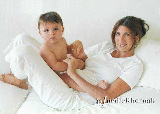 The classic elegance of mom and child in a clean white couch and background.