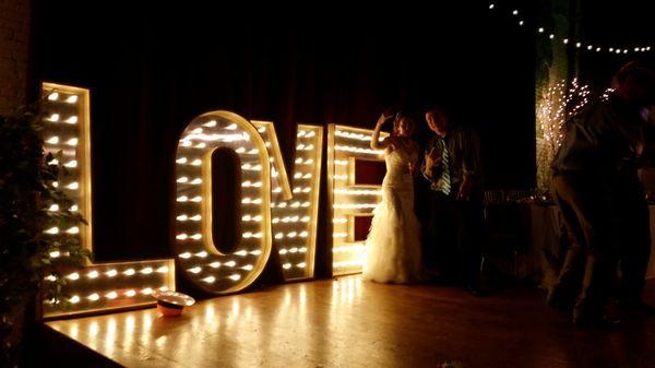 Our president and a very happy bride posing next to a set of our 5' lighted marquee love letters that we rent.