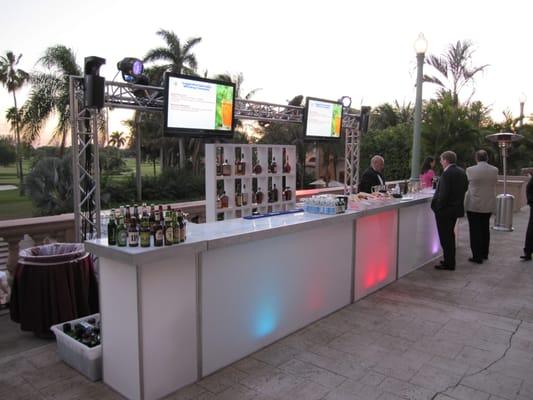 Custom lit bar with overhead video monitors highlight featured cocktails and event information.