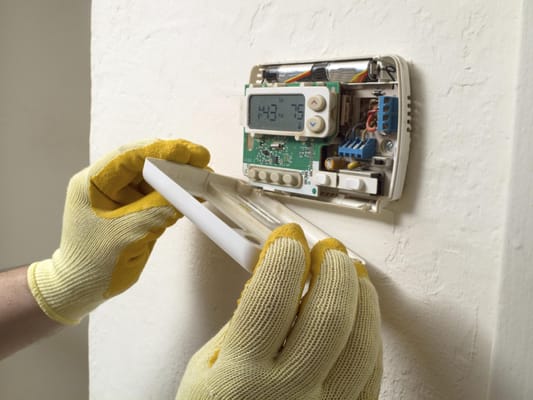 Technician checking thermostat for proper connections