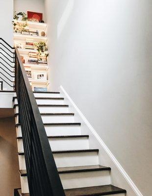 A built-in bookcase with recessed lighting takes this striking iron staircase up another notch.