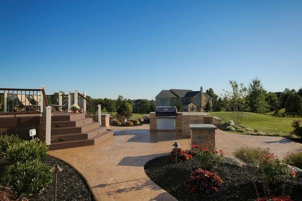 Two-tier stamped concrete patio with outdoor kitchen and custom designed deck.