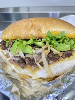 Torta with bistec, lettuce, avocado, grilled onions, cheese and refried beans.