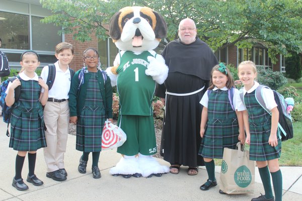 Students welcomed to school by Bernie and Father Tom.