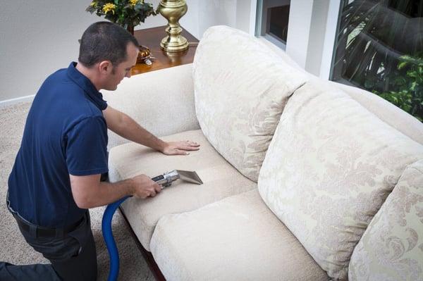 man cleaning upholstery with specialized machine.