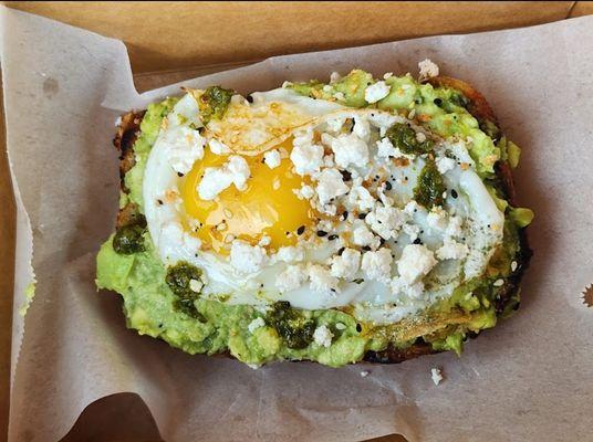 Avocado Toast, served on a toasted Rosemary Bread, sunny side up egg, topped with feta and everything bagel seasoning