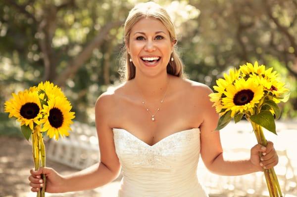 natural light bridal portrait of a happy bride with sunflowers during a summer wedding at the museum of natural history in SB.