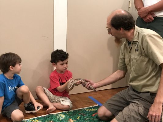 Brian holds a monitor lizard (I think?) while a child touches it.