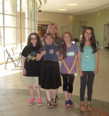 Sophia, Anna Lee, Abby, and Mikayla are holding the World War II scrapbook that their class made...