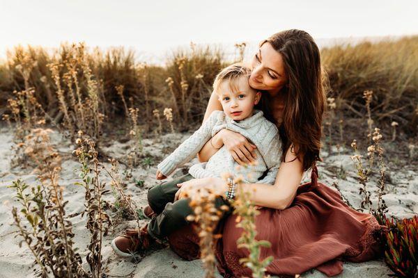 Mom and son at sunset on the beach with flowers.