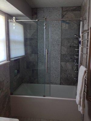 12" x 24" travertine tub surround with mosaic accent on center of back wall and 3 foot recess shampoo shelf.