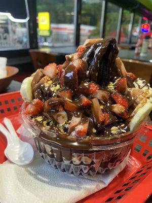 Acai Bowl Traditional (16oz) with strawberries, bananas, granola, Nutella, and milk powder.