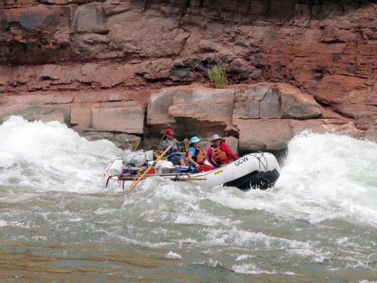 Oar boat going through a rapid.