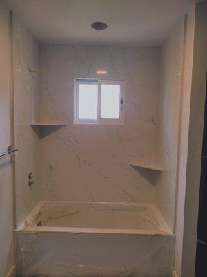 Here we did a custom quartz tub surround with 2 corner shelves.