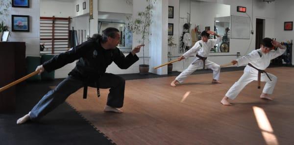 Instructor Charles and Jr. Warriors practicing a short stick form.