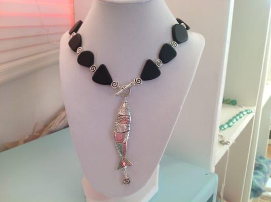 Black recycled beach glass and sterling silver plated fish necklace with clasp in the front.