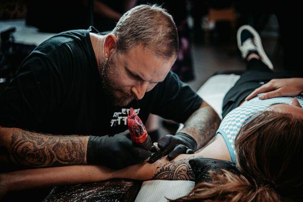 Joe with Red Letter Tattoo working on a customer.