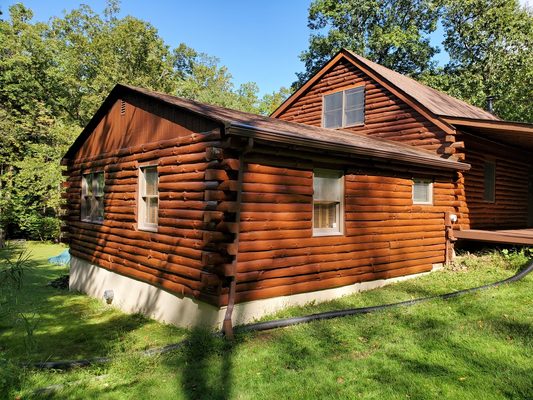 Log cabin hand brushed using oil based semi transparent coating.