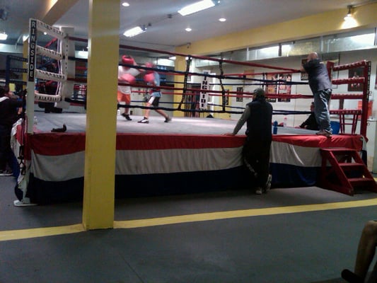 A coach offers feedback while a parent observes his son's sparring match.