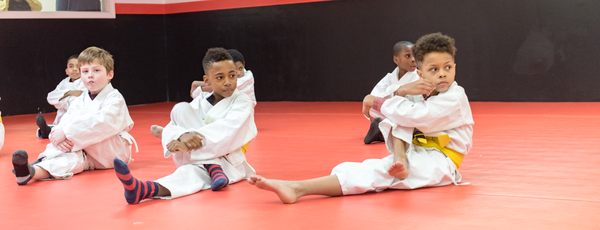 Kids jiu jitsu stretching out.