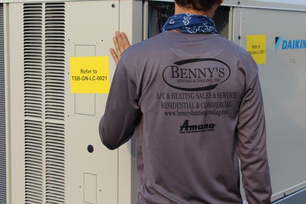 A technician is inspecting the new unit that had just arrived to the rooftop and is finishing the install.