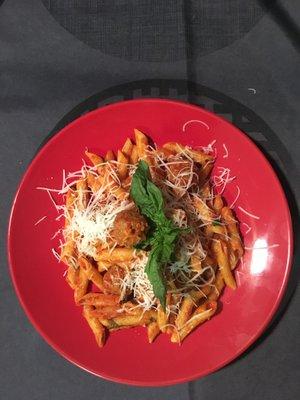 Penne with tomato sauce and meatballs, topped with basil and parmesan cheese