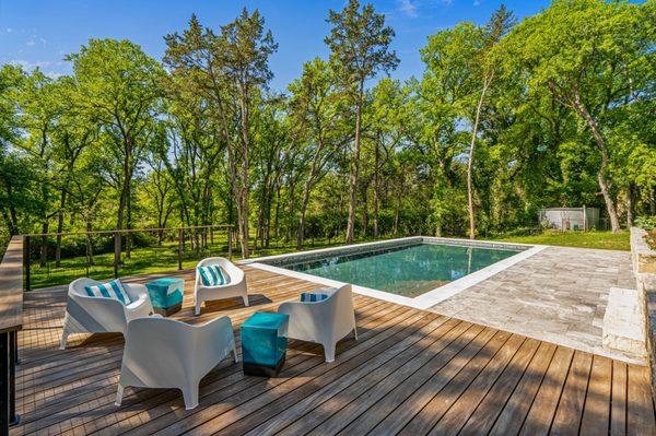 Escape to your own private retreat with this stunning natural pool featuring clean lines, travertine decking, and warm wood accents.