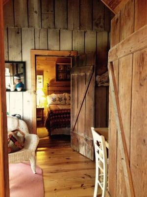 View of common area and bedroom from the bathroom in the stone cottage. Rustic charm at its finest.