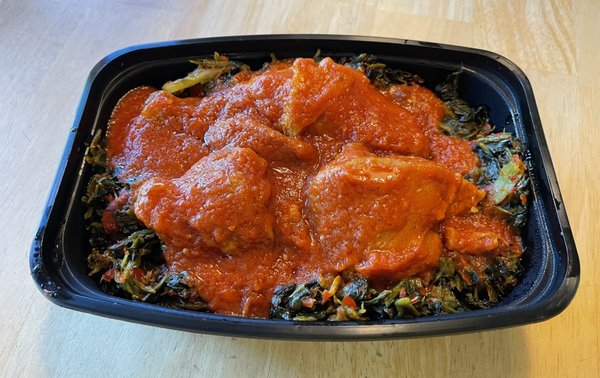 Efo riro (spinach stew) topped with chicken and sauce