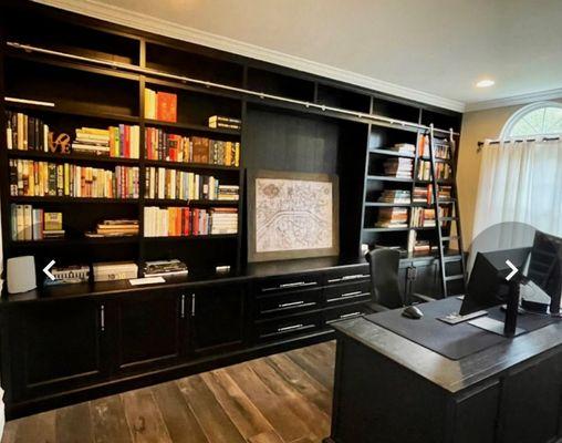 Wall to wall, ceiling to floor custom bookshelves with sliding ladder. Black finish featuring soft closing drawers and doors