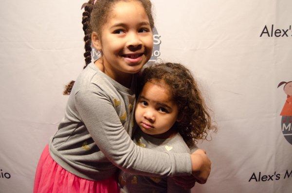 Two adorable students posing in front of our photo wall at our Winter Recital at Beat Kitchen