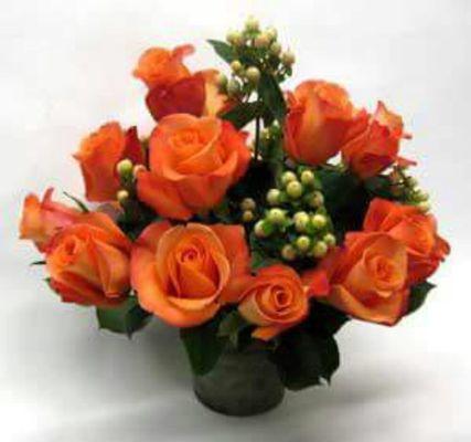 18 vibrant orange roses with hypericum.