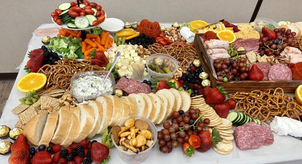 Grazing table bursting with fruit, chocolates, meats and cheese.