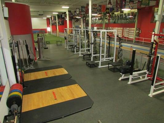 A view of part of the weight room with a glimpse of the 35yd turf and 6 lane 60yd track.