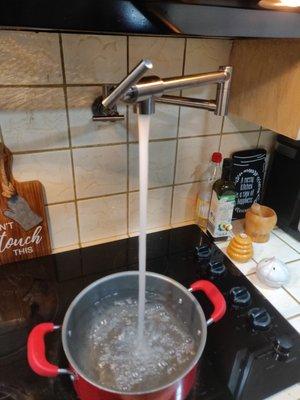 Pot filler cold water line and faucet installed above stove.