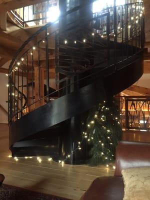 The spiral staircase that leads upstairs to a library area.