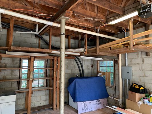 Before picture of garage with overhead rafters and wood planks.