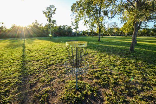 Disc golf baskets placed throughout a mix of open fields and wooded areas