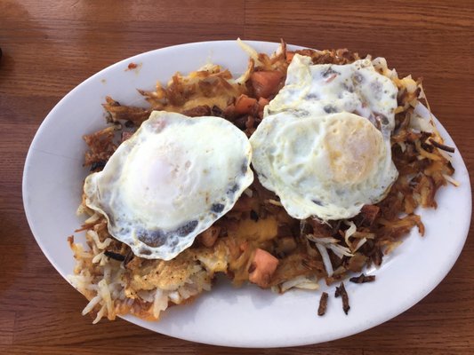 Wake Up Call Stacker- Hash browns with Cheddar Cheese, 2 eggs,  tomatoes, covered in hollandaise sauce with crumbled up bacon and toast