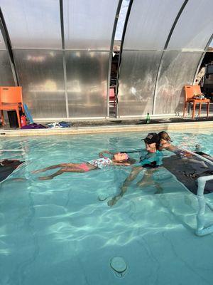 Mrs Kris teaching Nova how to float on her back in survival swim class