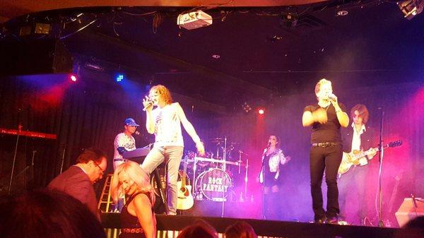 From left to right, Elton John, Lou Gramm, and Jon Bon Jovi all singing together at the end for the grand finale.