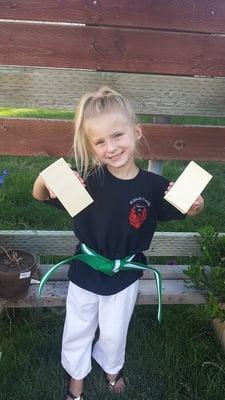 One of our students after a belt testing. She is showing off the board she broke :)