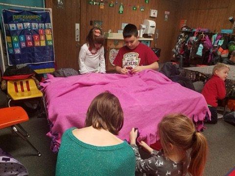 4th graders and kindergarteners make blankets for the homeless.