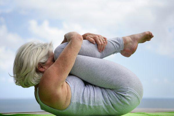 Client hugging knees to chest after finishing her yoga practice.