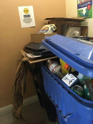 Overflowing stinking rotting trash in the trash room at the end of the hall.