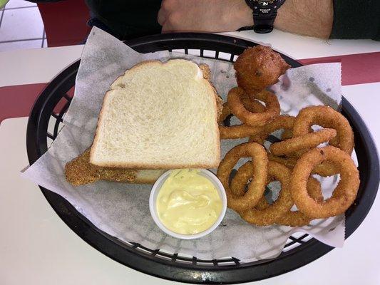 Catfish sandwich with homemade tartar sauce, hush puppy, and onion rings