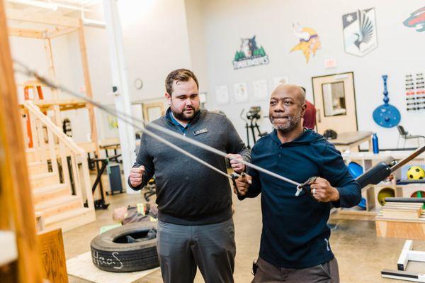 Occupational therapist assisting with stabilizing exercises in St. Paul's industrial rehabilitation gym.