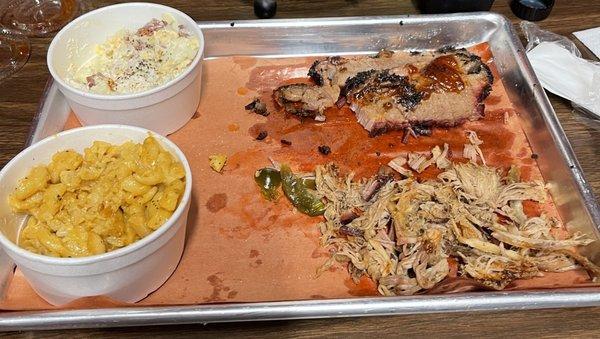 Half-eaten brisket, pulled pork, potato salad, and mac and cheese.