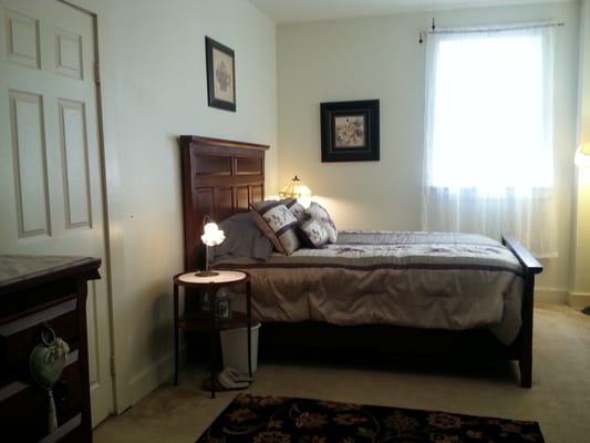 Queen size bed in room with TV and CD player has a large dresser too.