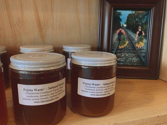 Pejuta Wašte Infused Honey display with photo of Lakota Made employees harvesting plants